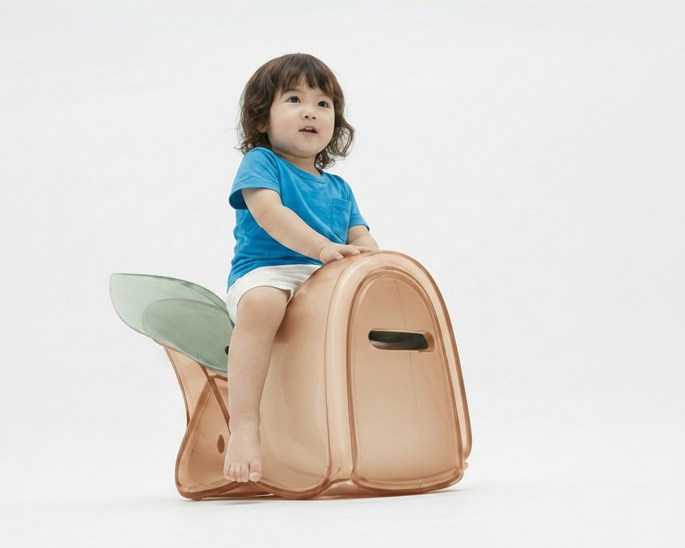 A young child sits on the apricot body with green wing colourway of the cicada chair, hand resting on the wing flange — the chair's two behaviors (sit-on and strike) embodied in one image.